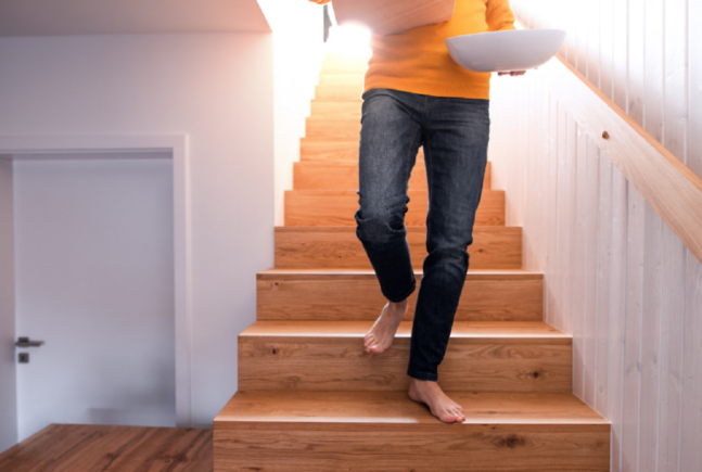 Person walking down the stairs barefoot with box and bowl